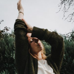 Eine Fraue in einer Yoga Pose mit ausgestreckten Armen über dem Kopf