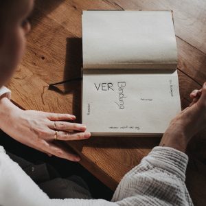 Ein aufgeklapptes Buch und eine Frau, die dort hineinschreibt